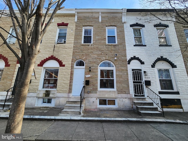 townhome / multi-family property featuring entry steps, stone siding, and cooling unit