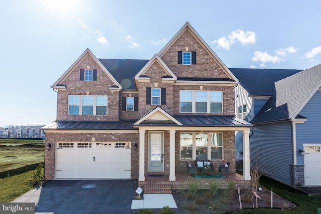 view of front facade featuring brick siding, covered porch, an attached garage, a standing seam roof, and driveway