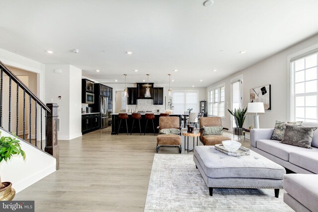 living area featuring stairs, light wood-type flooring, baseboards, and recessed lighting