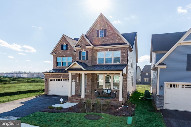 view of front of home with aphalt driveway, brick siding, a porch, an attached garage, and a standing seam roof