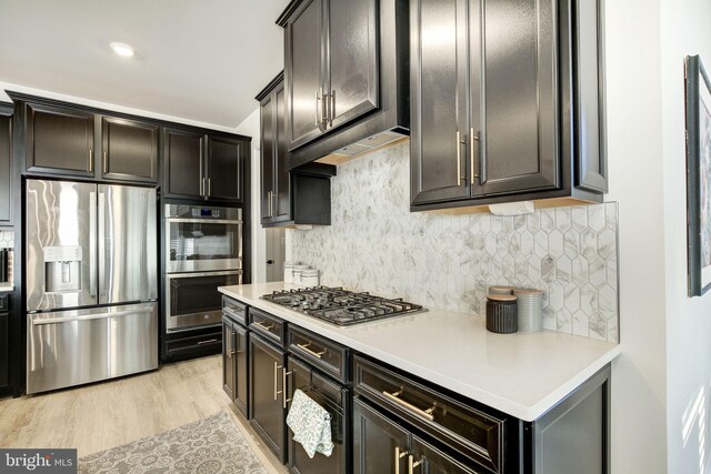 kitchen featuring appliances with stainless steel finishes, light wood-type flooring, light countertops, and tasteful backsplash