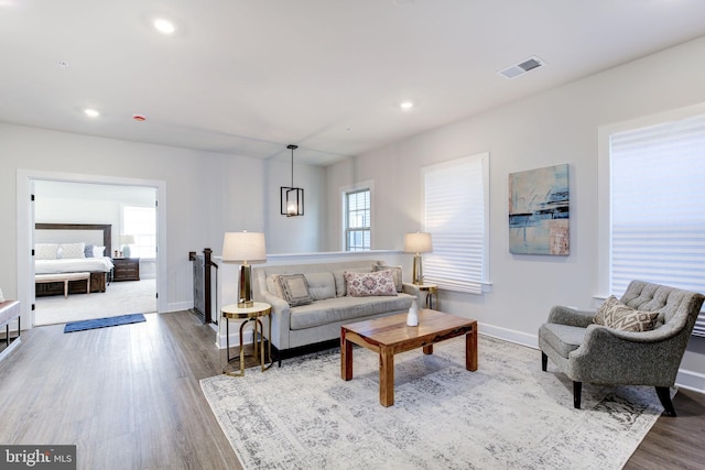 living area with recessed lighting, visible vents, baseboards, and wood finished floors