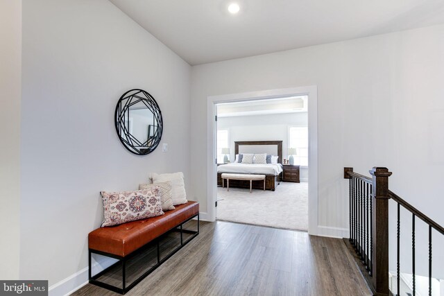 hall featuring an upstairs landing, baseboards, and wood finished floors