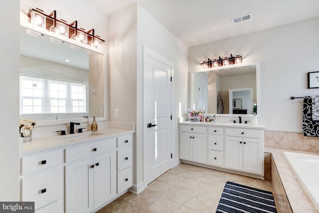 bathroom featuring a relaxing tiled tub, visible vents, and vanity