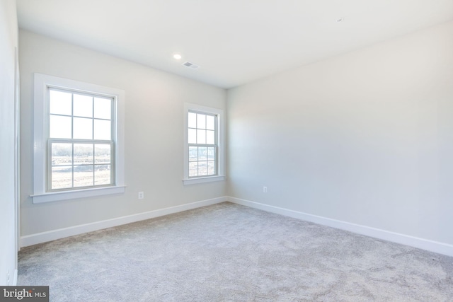 unfurnished room featuring carpet flooring, visible vents, and baseboards