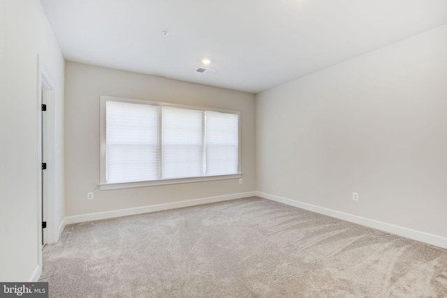 carpeted spare room with visible vents and baseboards