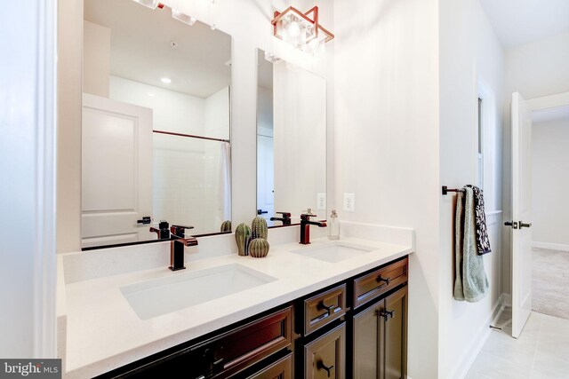 bathroom featuring tile patterned flooring, a sink, baseboards, and double vanity