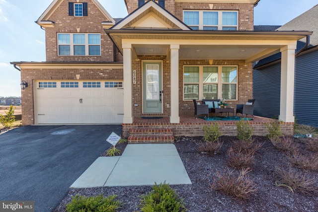 view of front of house featuring driveway, covered porch, and brick siding