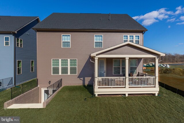 back of property with a yard and a shingled roof