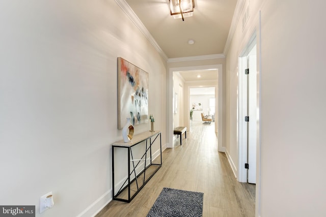 corridor with baseboards, light wood-type flooring, visible vents, and crown molding