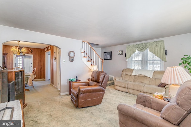 living area with baseboards, arched walkways, light colored carpet, stairs, and a chandelier