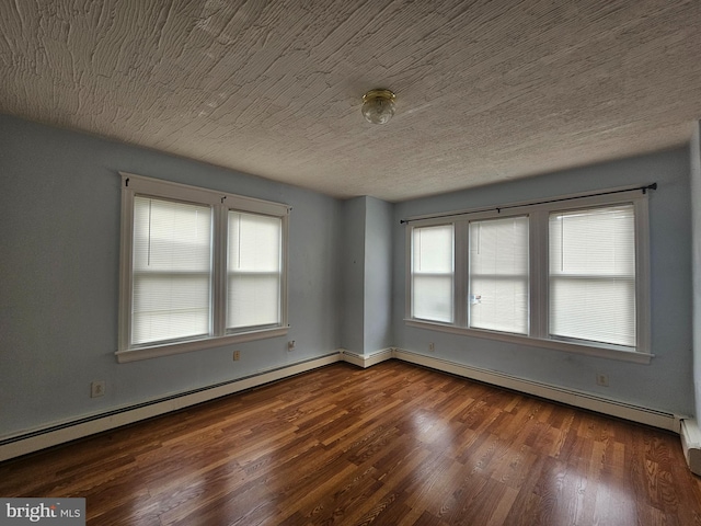 empty room with a textured ceiling, baseboard heating, and wood finished floors