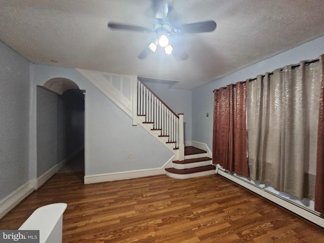 interior space with ceiling fan, wood finished floors, baseboards, stairs, and baseboard heating