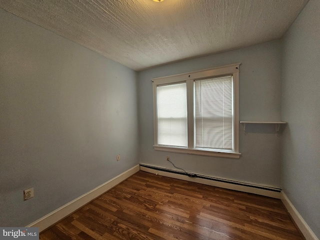 empty room with baseboards, a baseboard heating unit, dark wood finished floors, and a textured ceiling