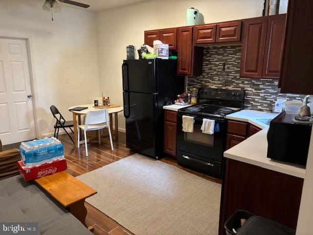 kitchen with ceiling fan, wood finished floors, light countertops, decorative backsplash, and black appliances