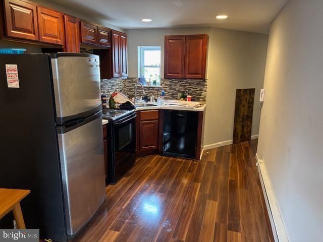 kitchen featuring tasteful backsplash, dark wood-style floors, black appliances, a baseboard heating unit, and a sink