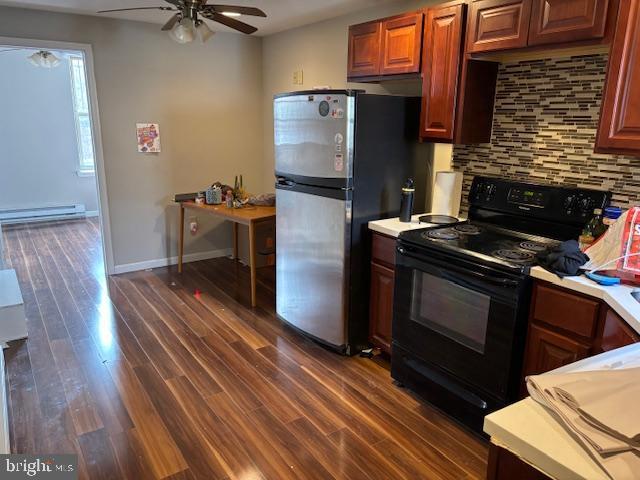 kitchen with dark wood-style flooring, light countertops, black range with electric stovetop, decorative backsplash, and freestanding refrigerator