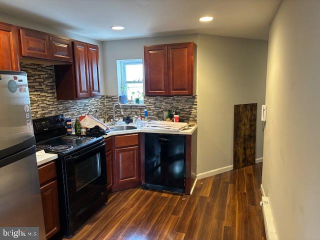 kitchen featuring black appliances, dark wood-type flooring, a sink, and light countertops