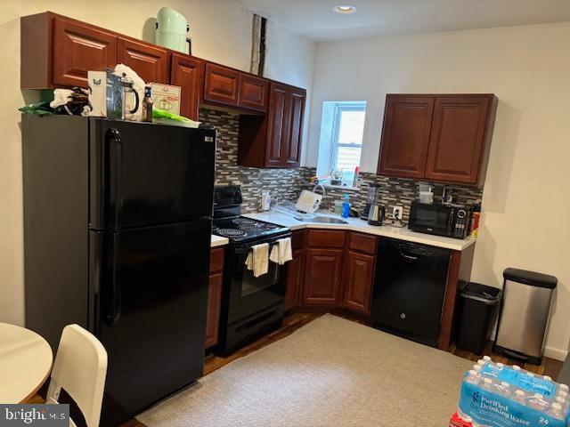 kitchen featuring black appliances, backsplash, a sink, and light countertops