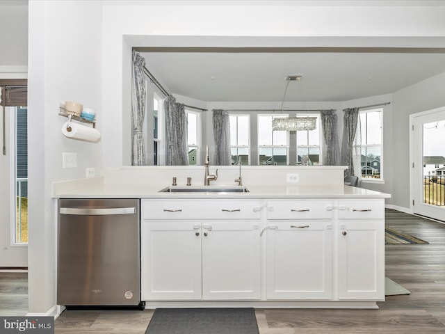 kitchen featuring a sink, white cabinetry, wood finished floors, and stainless steel dishwasher