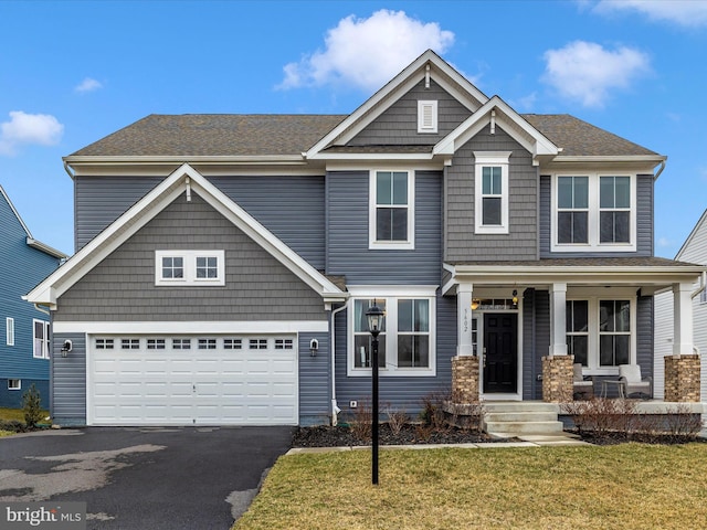 craftsman house with a porch, an attached garage, a front yard, and driveway