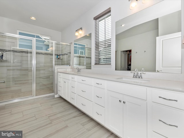 bathroom with double vanity, recessed lighting, a stall shower, and a sink