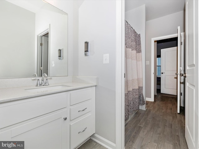 full bath with baseboards, wood finished floors, and vanity