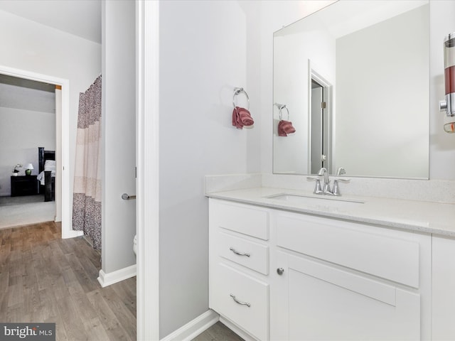 bathroom with toilet, vanity, baseboards, and wood finished floors