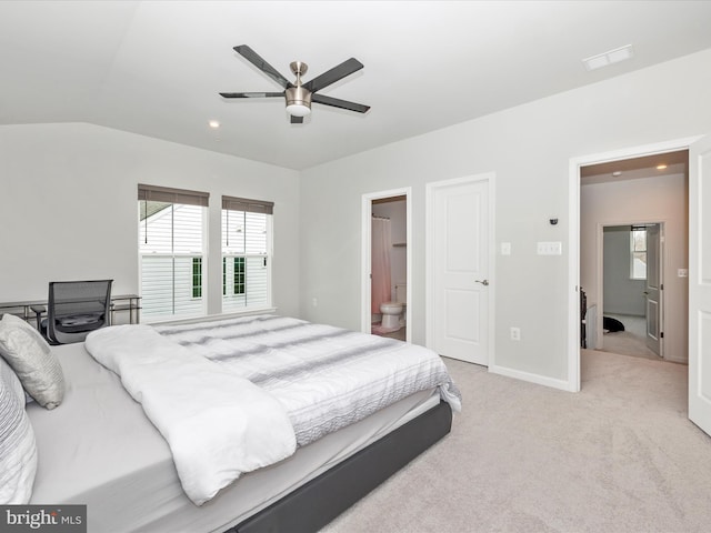 bedroom with visible vents, ensuite bathroom, baseboards, light colored carpet, and vaulted ceiling