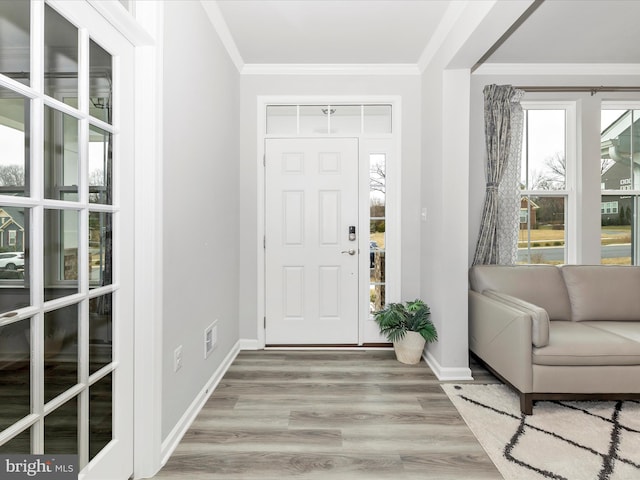 foyer featuring visible vents, baseboards, wood finished floors, and crown molding