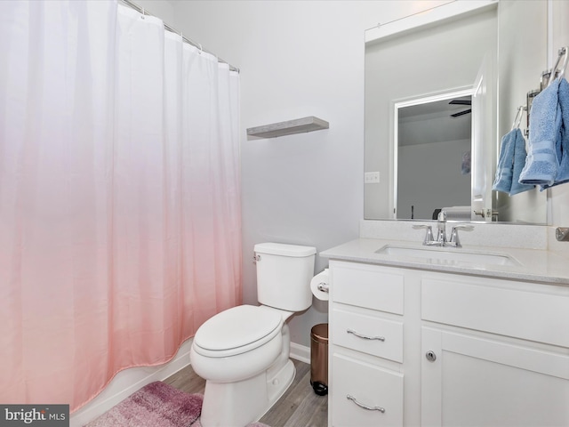 bathroom with toilet, vanity, baseboards, and wood finished floors