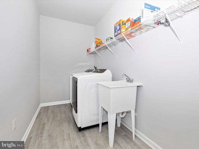 washroom with baseboards, washer / clothes dryer, laundry area, and light wood finished floors