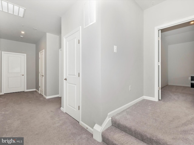 hall with visible vents, baseboards, and carpet floors