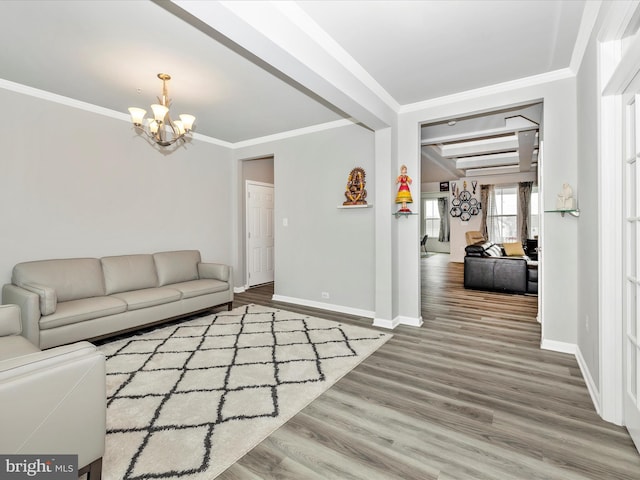 living room featuring baseboards, a notable chandelier, wood finished floors, and ornamental molding