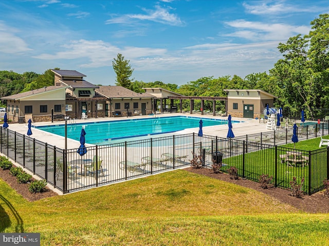 community pool with a patio area, a yard, and fence