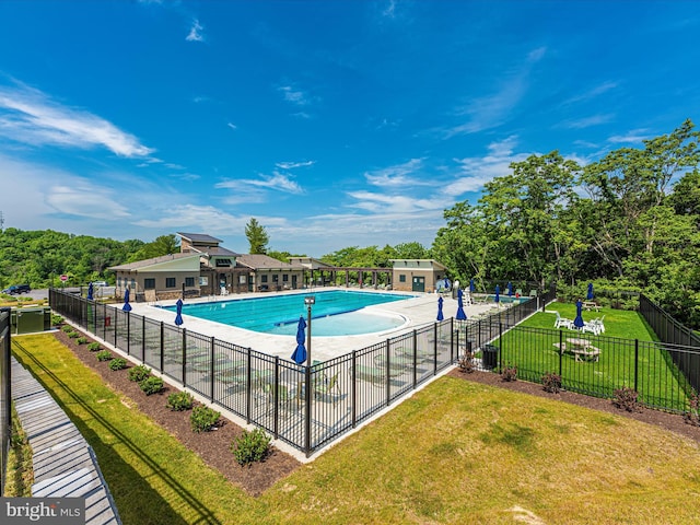 community pool with a patio, a yard, and fence