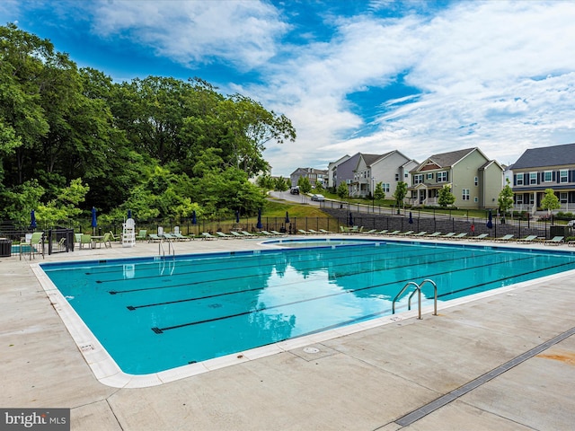 community pool with a patio area, a residential view, and fence