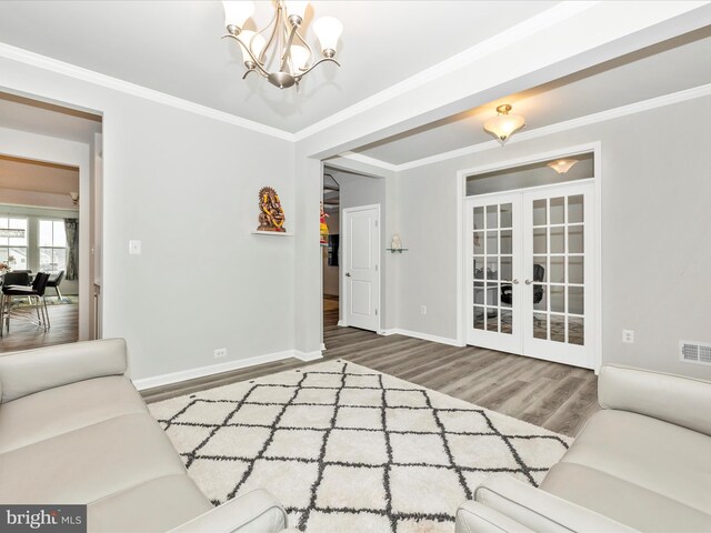 living room with french doors, a notable chandelier, wood finished floors, and ornamental molding