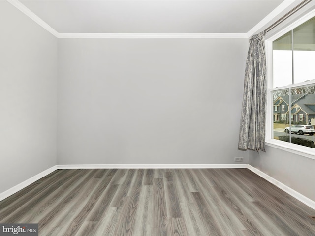 empty room featuring crown molding, baseboards, and wood finished floors