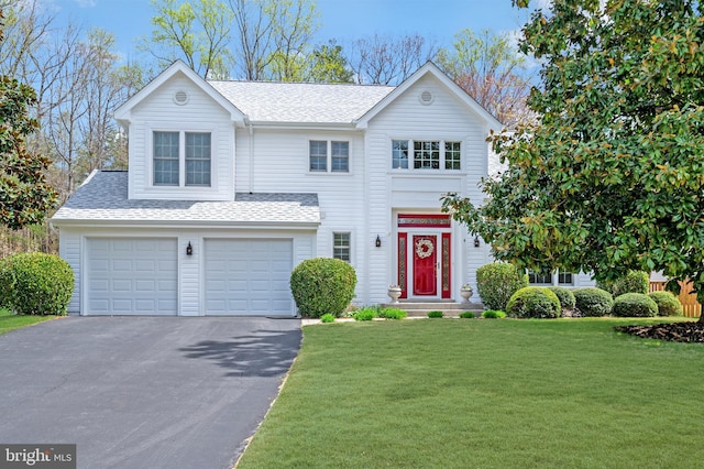 traditional home with a front lawn, an attached garage, aphalt driveway, and a shingled roof