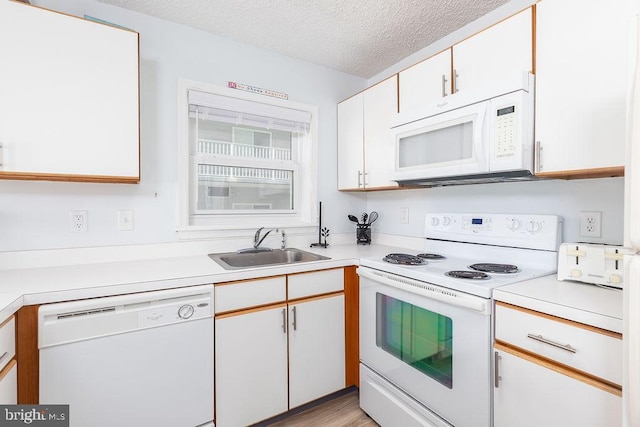 kitchen with a textured ceiling, light countertops, white appliances, and white cabinets