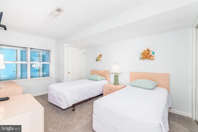 carpeted bedroom featuring a textured ceiling, visible vents, and baseboards