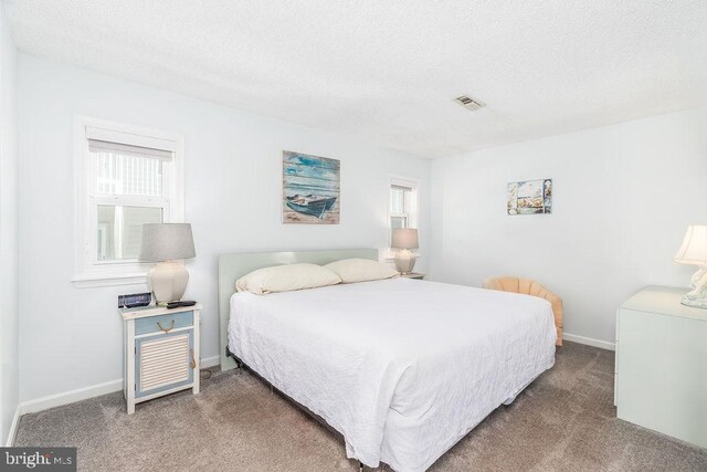 carpeted bedroom with baseboards, visible vents, and a textured ceiling