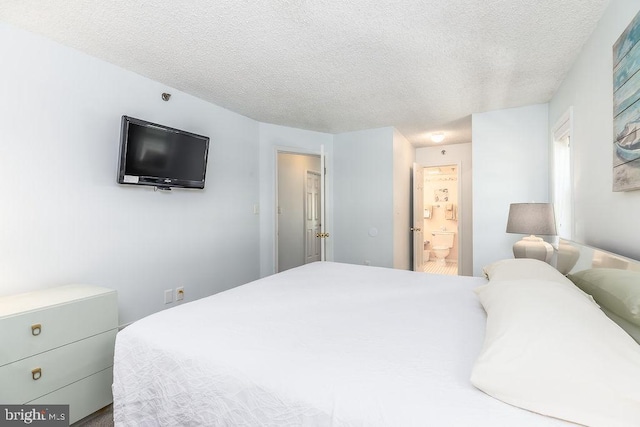 bedroom with a textured ceiling and ensuite bath