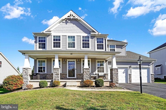 craftsman inspired home with a porch, aphalt driveway, a garage, stone siding, and a front yard