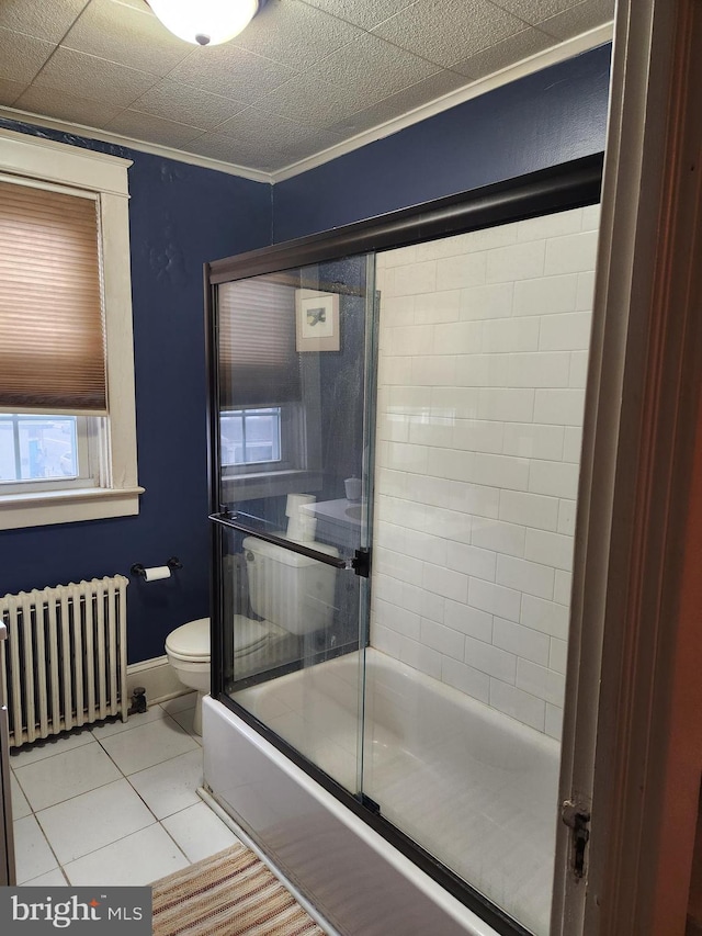 bathroom featuring tile patterned flooring, toilet, shower / bath combination with glass door, radiator, and crown molding