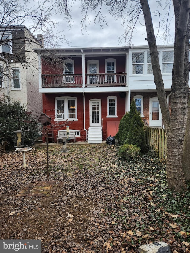 back of house with entry steps, brick siding, and a balcony