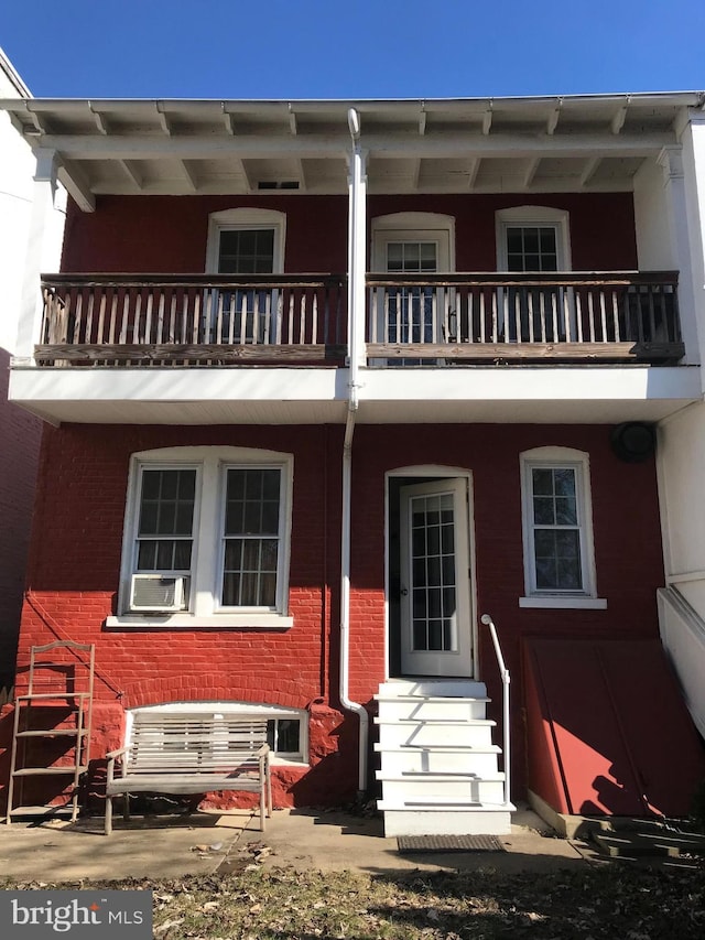 view of front of home with entry steps, a balcony, cooling unit, and brick siding