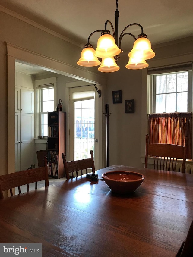 dining room featuring an inviting chandelier, ornamental molding, and wood finished floors