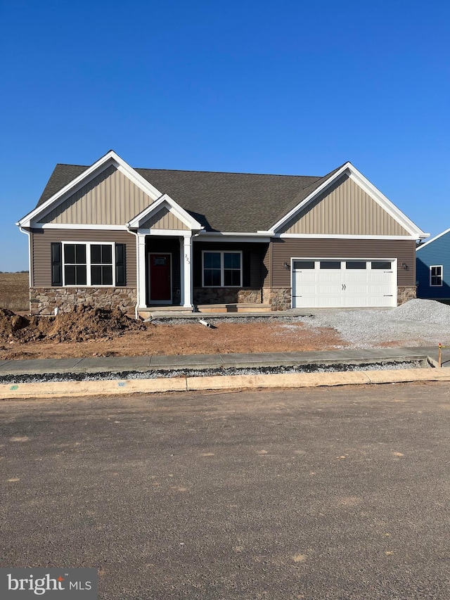 view of front of property with a shingled roof, an attached garage, board and batten siding, stone siding, and driveway